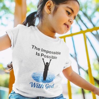 Bella+Canvas toddler t-shirt with “Impossible Toddler” design and faith-filled message, soft cotton, breathable and durable, Christian apparel for active toddlers and family matching, toddler girl in white t-shirt